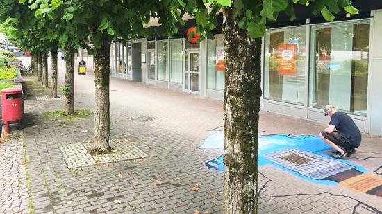 Gatubrunnen är ingen papperskorg. Här växer ett viktigt budskap fram utanför biblioteket i Karlskoga.